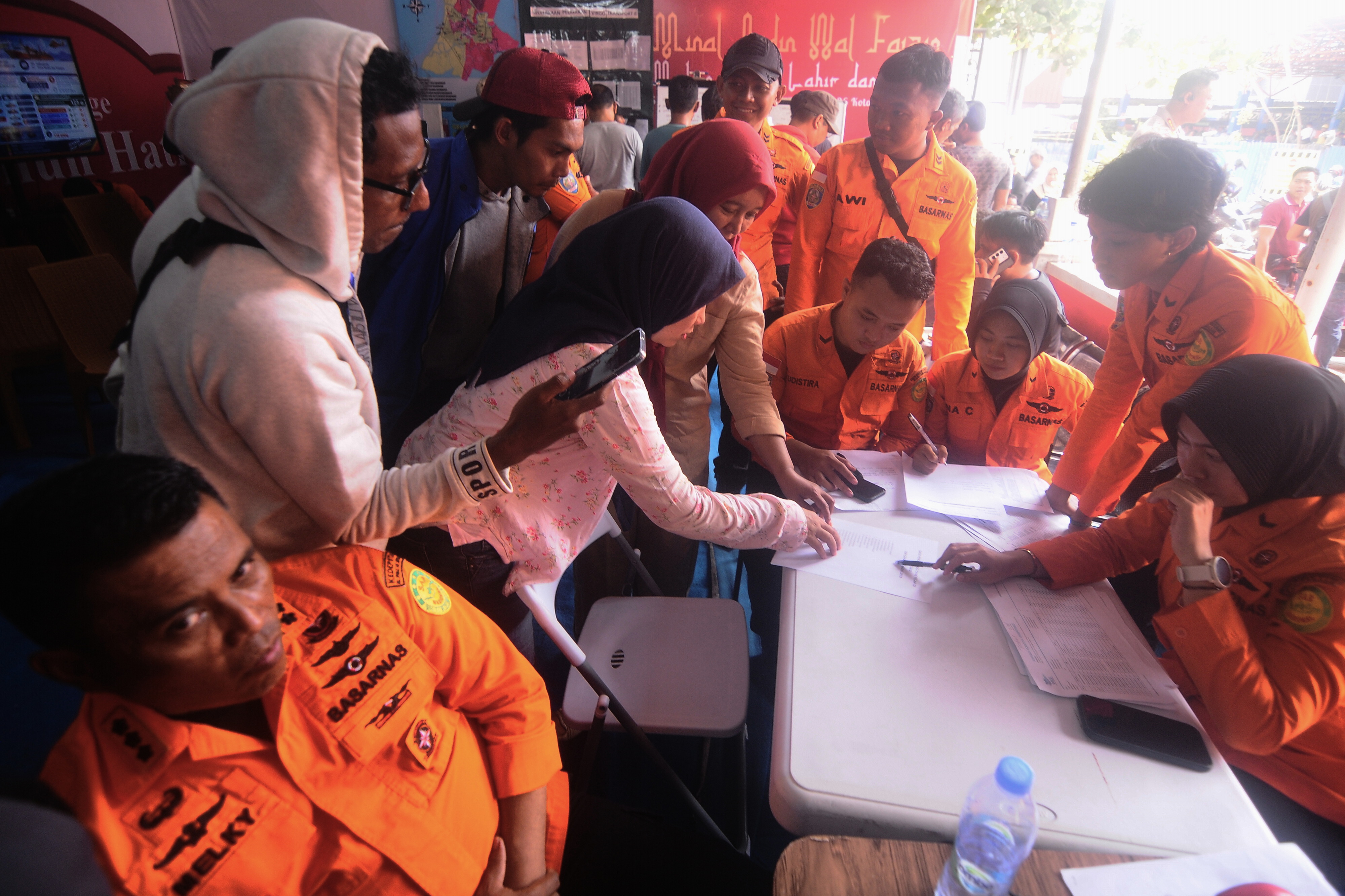 People look for the names of their family members on a passenger list after a ferry overturned in bad weather in the Java Sea, at the rescuers command center in Banjarmasin, South Kalimantan, Indonesia, Sunday, Sept. 13, 2026.